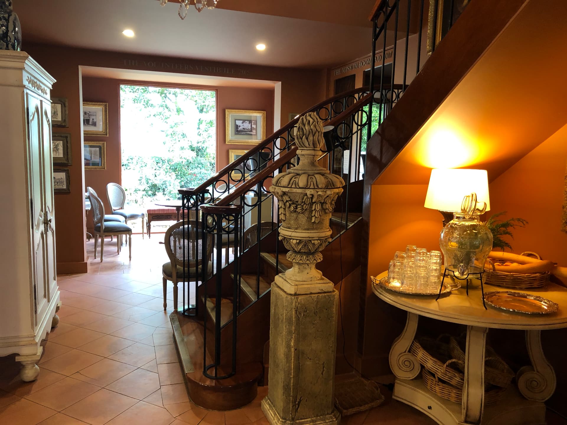 Entrance hall with staircase, stone urn and warm lamplight