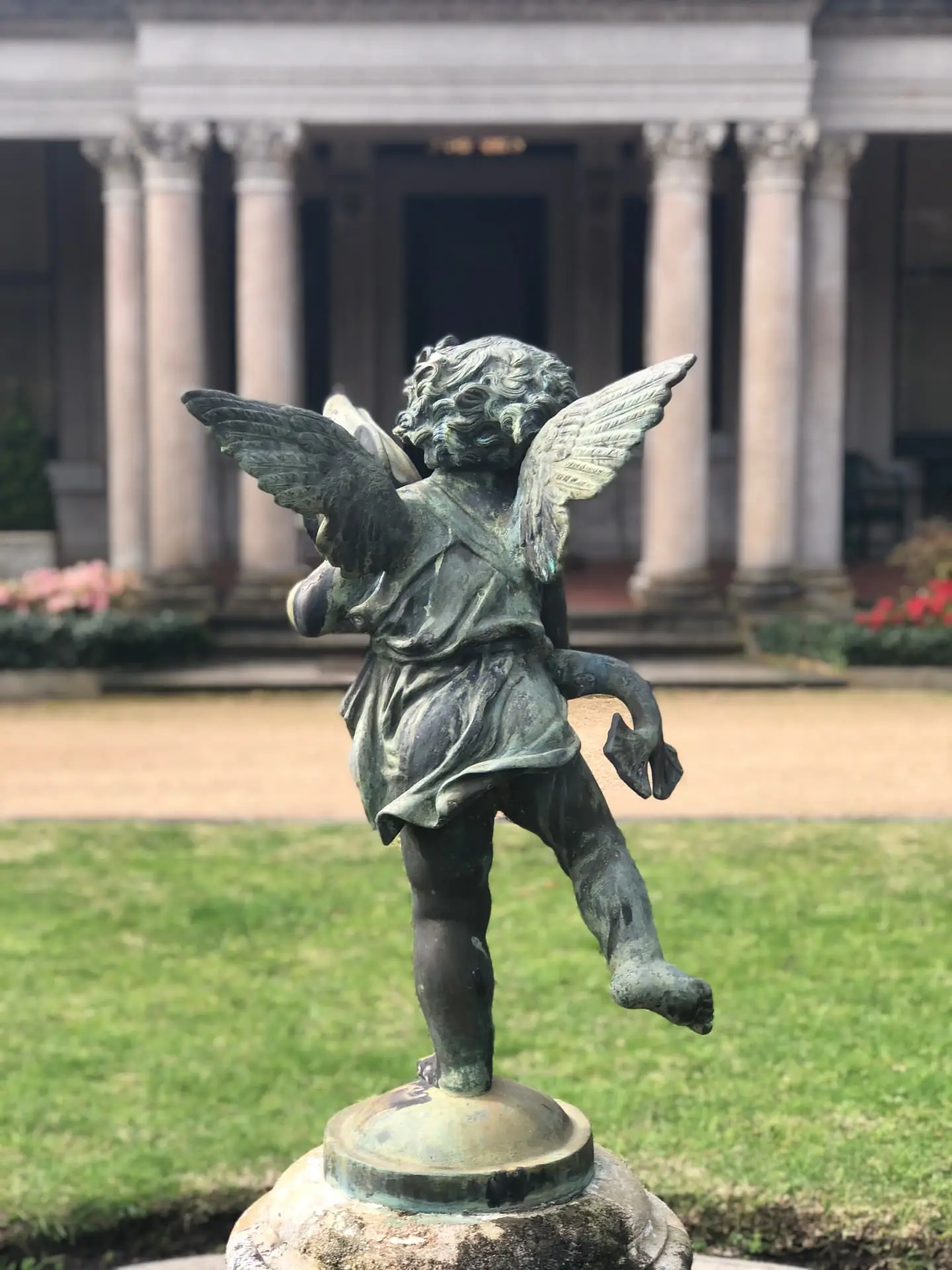Bronze cherub statue playing before the mansion's classical columns