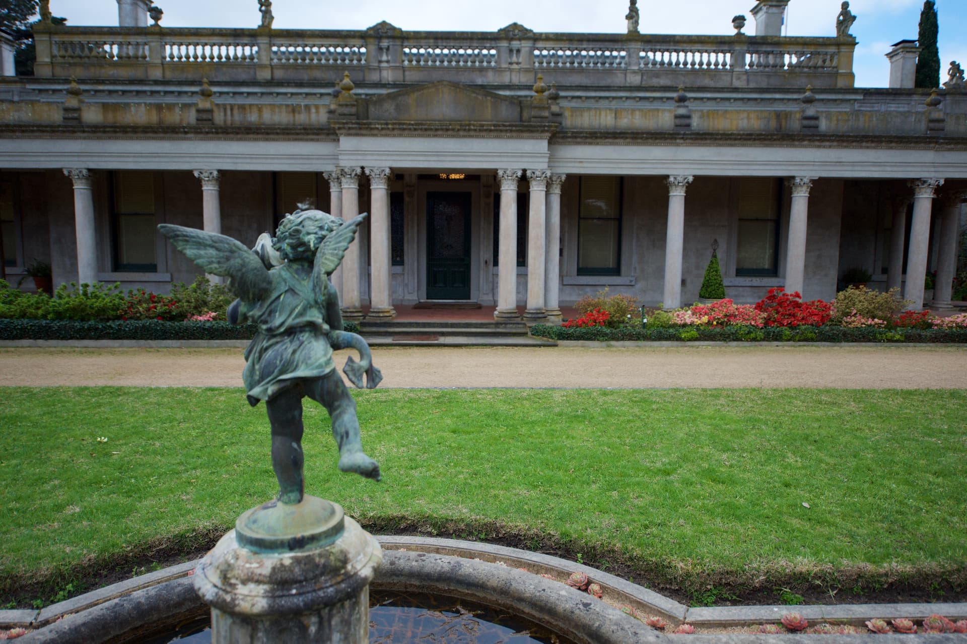 Bronze winged cherub fountain in front of the mansion's long colonnade