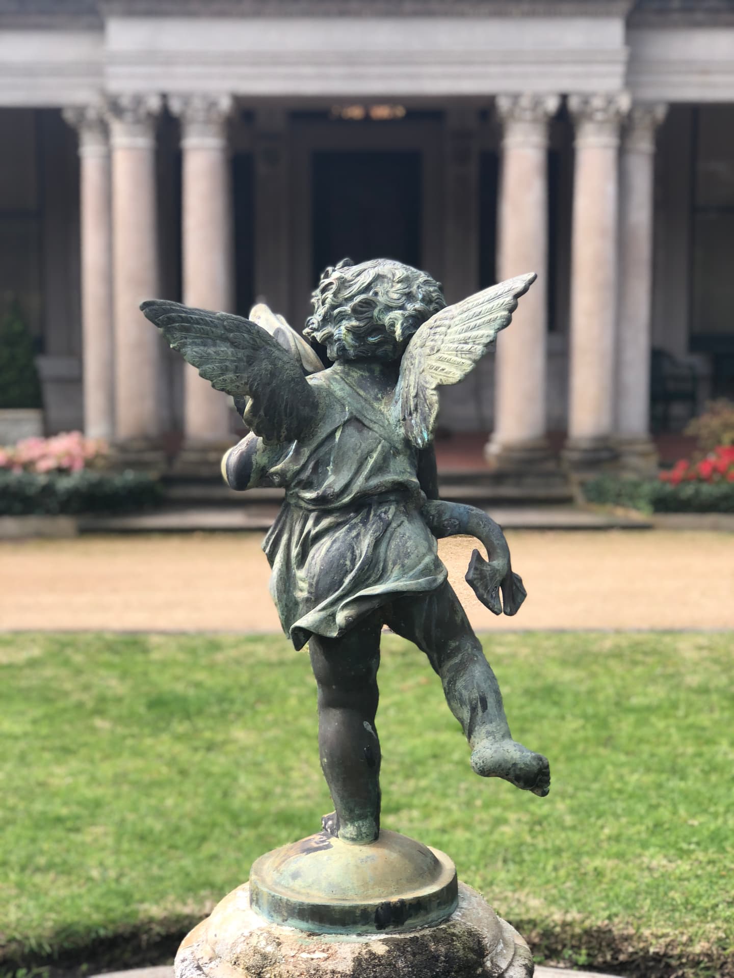 Bronze cherub statue playing before the mansion's classical columns